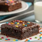 A close-up of a Cosmic Brownie with chocolate frosting and sprinkles