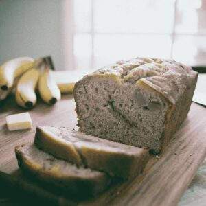 Freshly baked banana bread loaf sliced on wooden board showing moist tender crumb