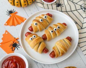 mummy hot dogs wrapped in crescent dough with candy eyes for Halloween