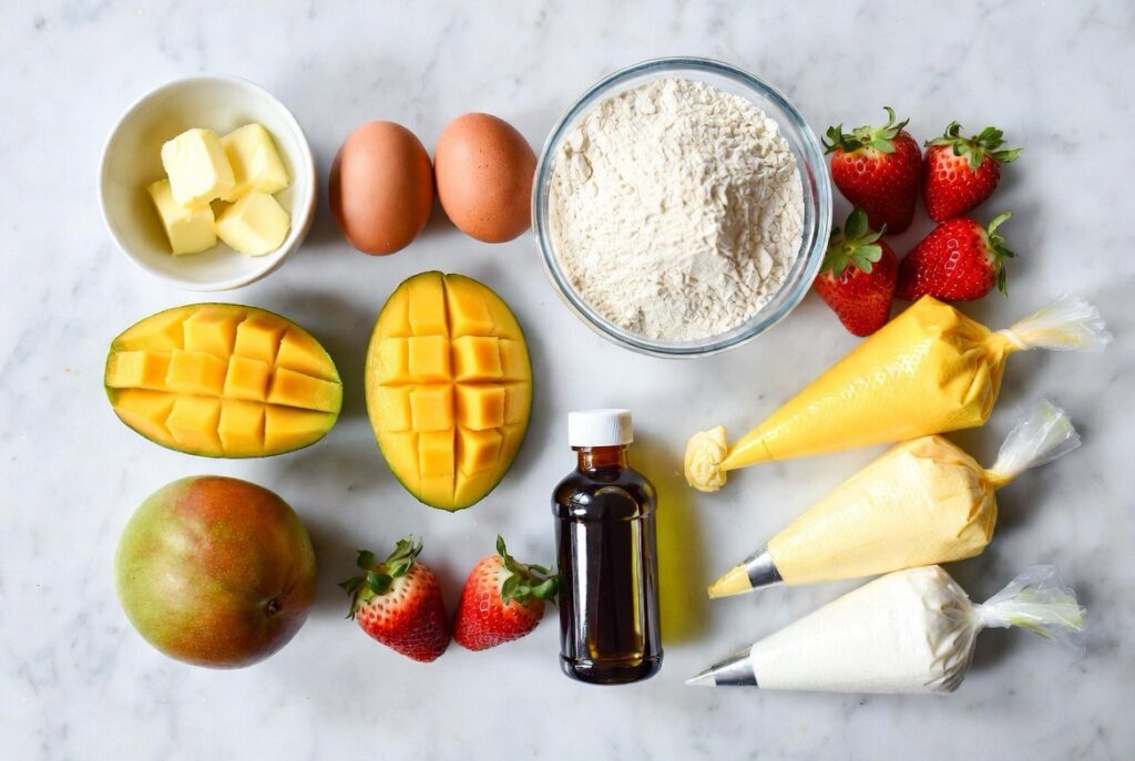 Cross section of mango strawberry cupcake showing vanilla cake with strawberry jam filling and ombre frosting

